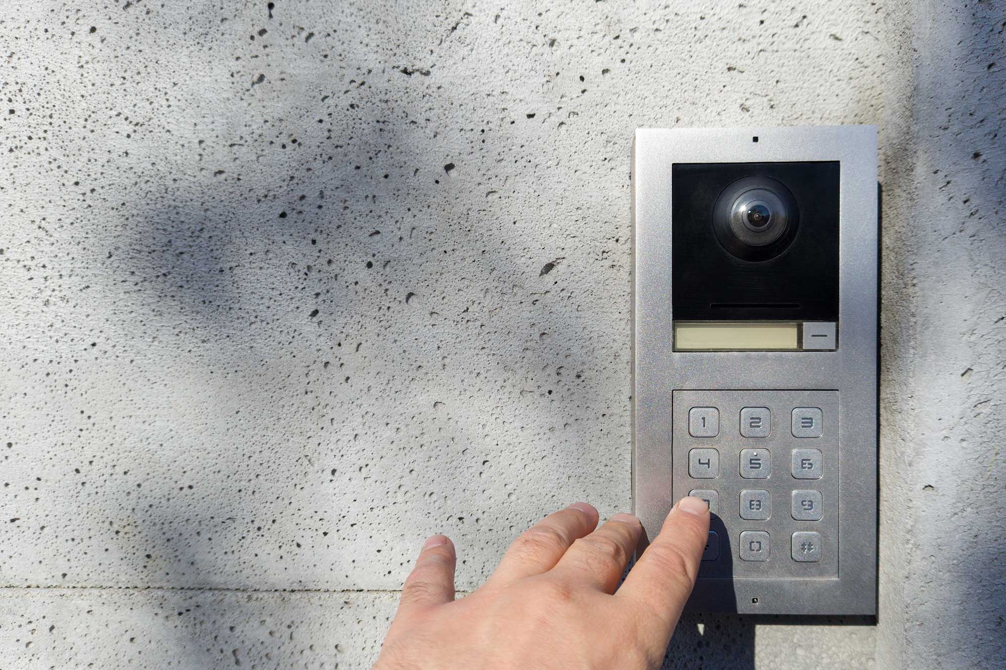 Närbild av en hand som trycker på knappsatsen av en porttelefon